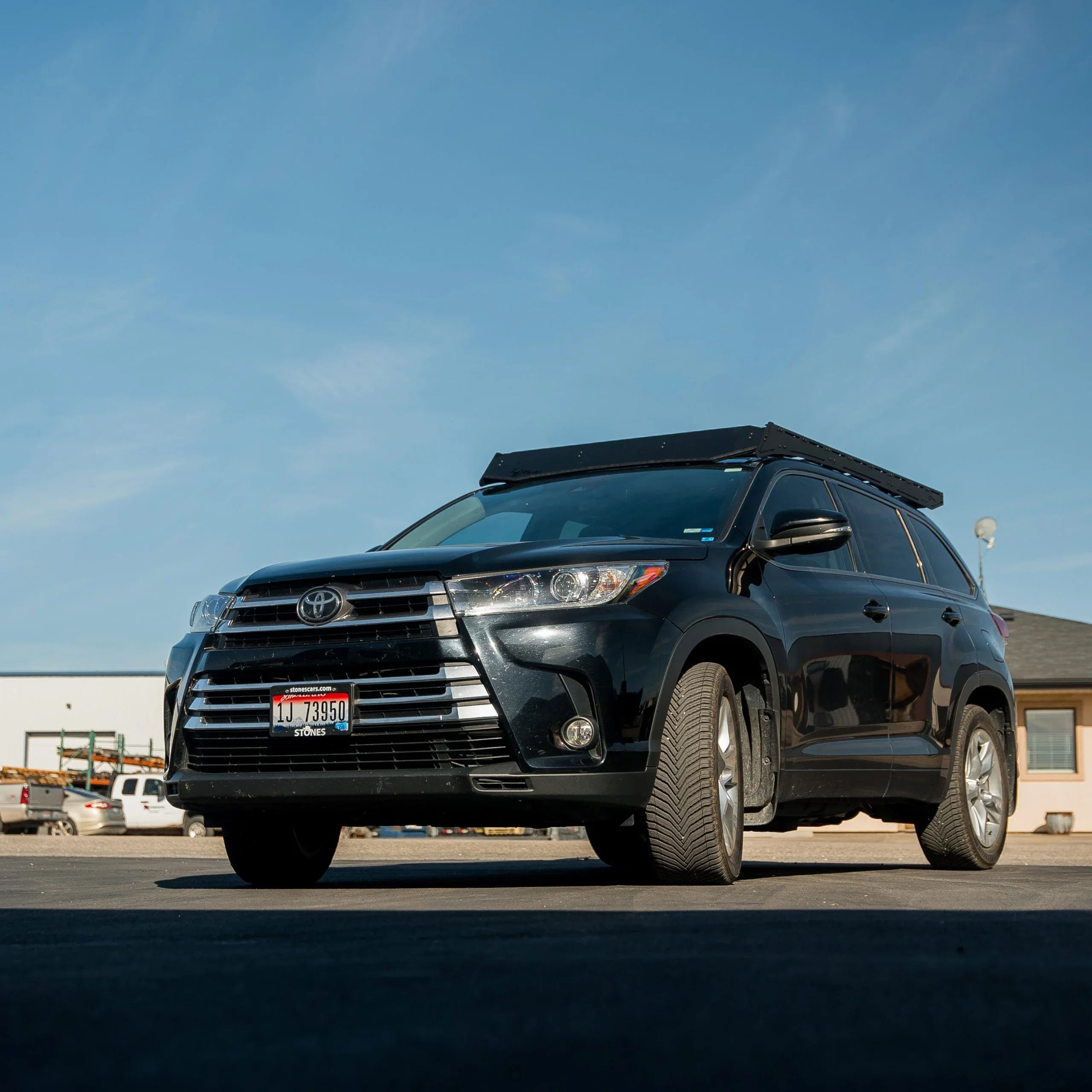 Black Toyota Highlander SUV with roof rack for overlanding camping accessories in parking lot
