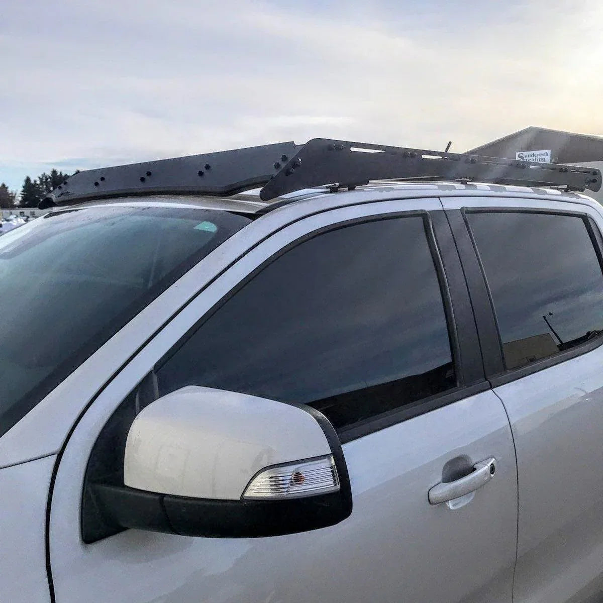 Close-up of a roof rack mounted on a white Toyota Tacoma, designed for overlanding gear.