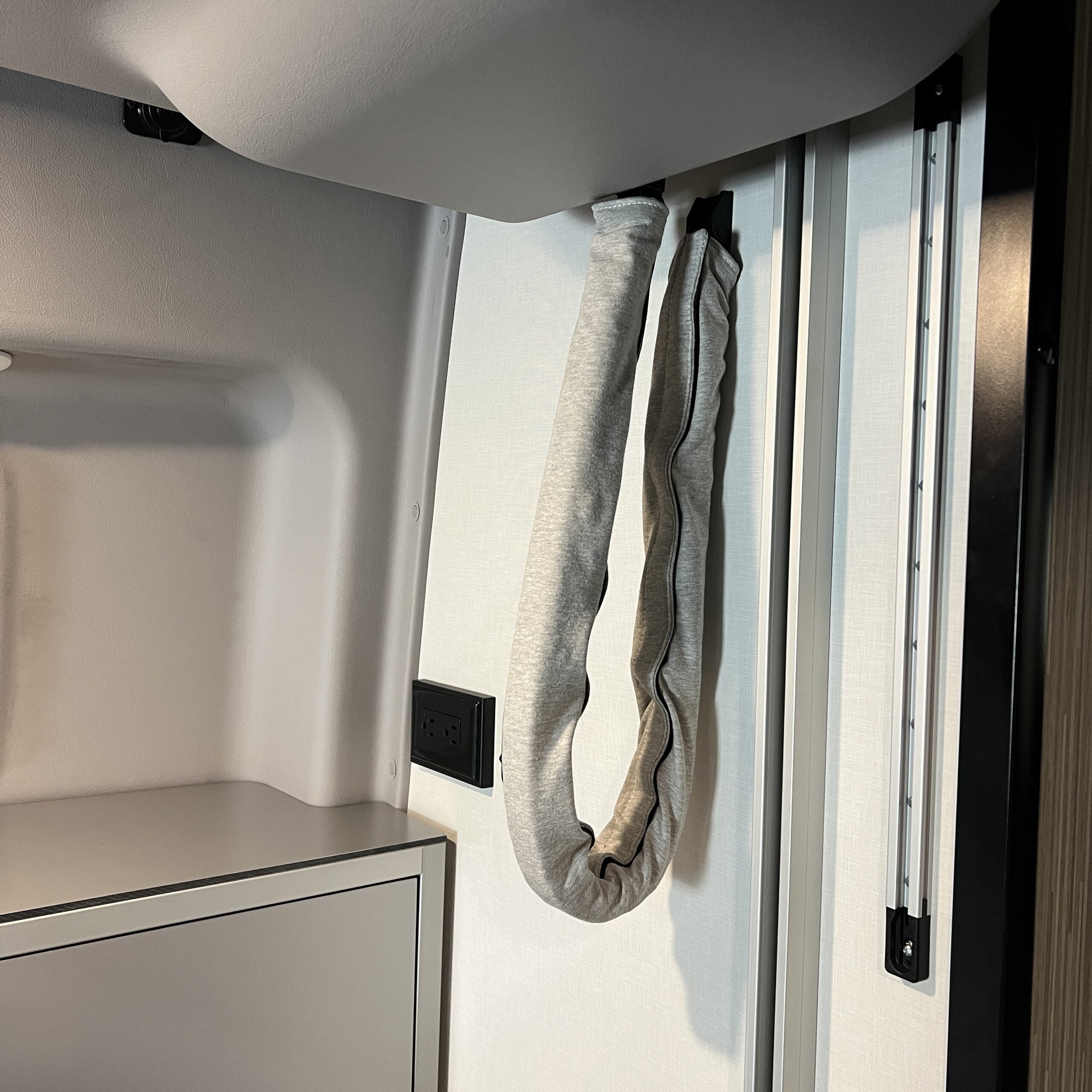 Interior camper wall with mounted storage strap and power outlet, overlanding gear accessory