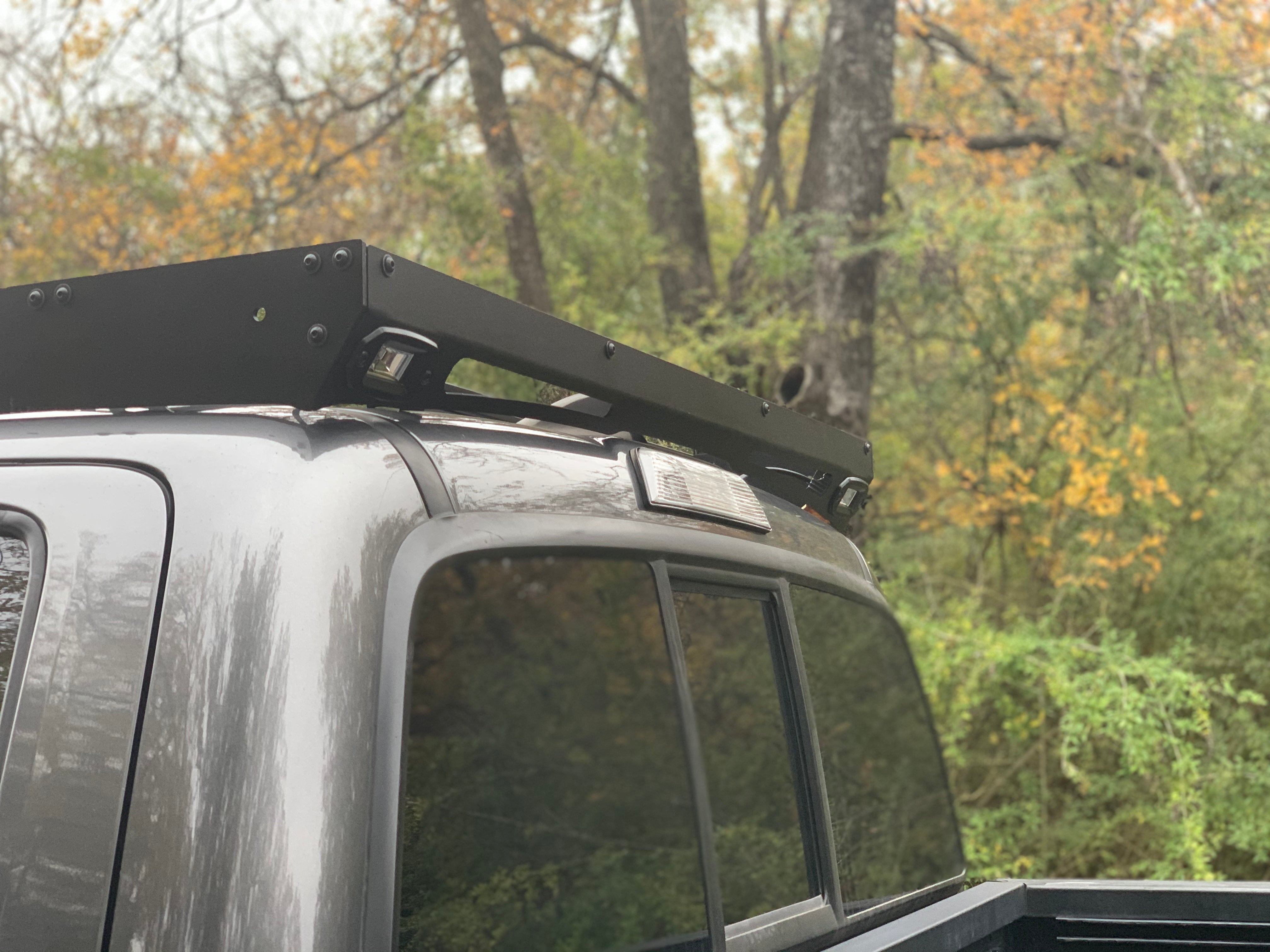 Black roof rack with integrated LED lights on a pickup truck, outdoor adventure setting