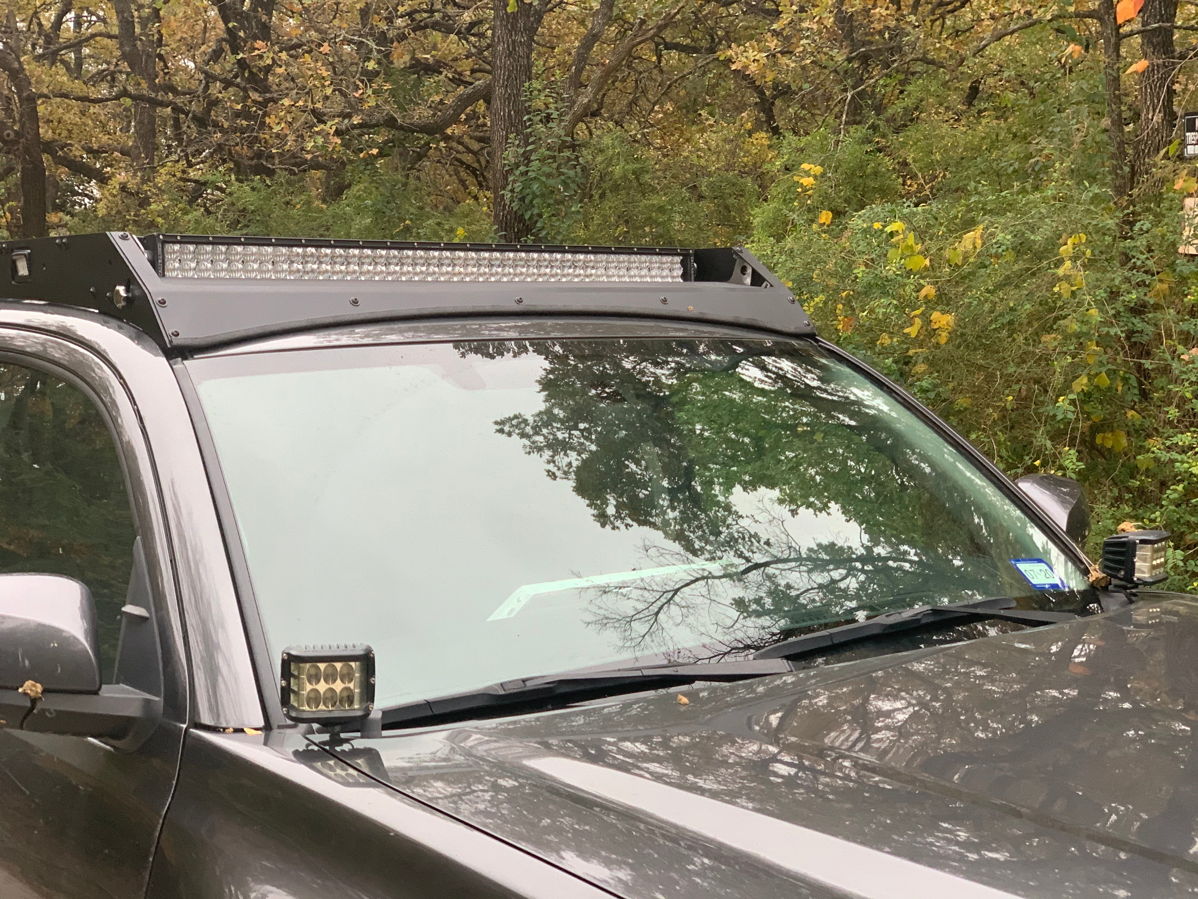 Toyota Tacoma with off-road LED light bar and pod lights in wooded outdoor setting