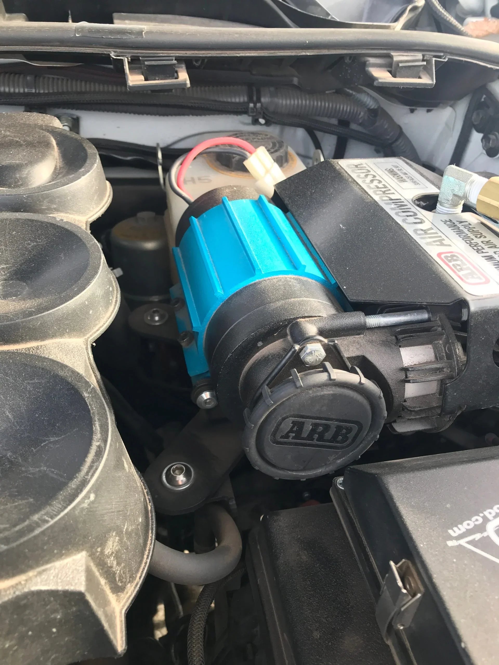 ARB air compressor installed in a vehicle engine bay for overlanding accessories