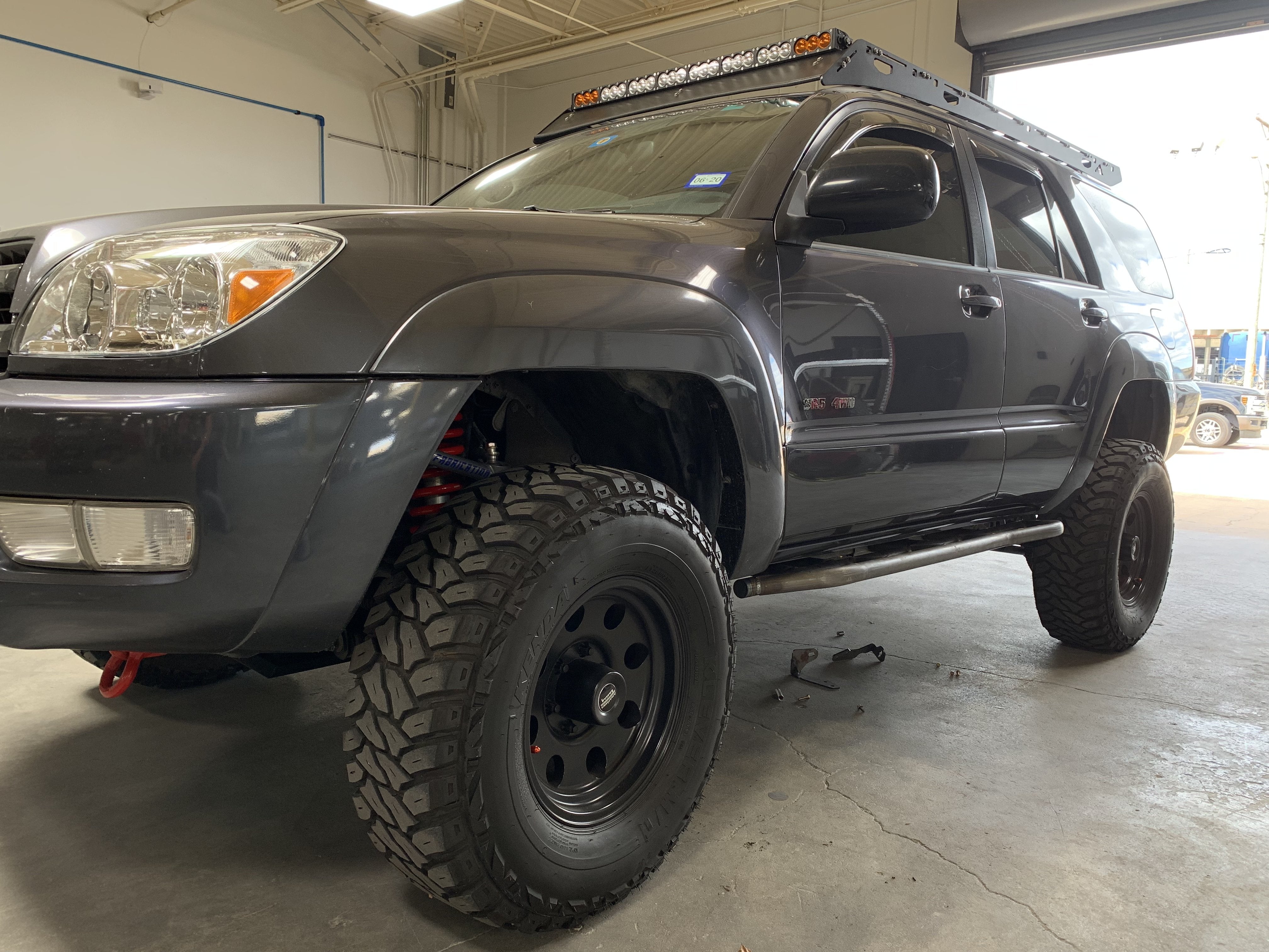 Lifted Toyota 4Runner with off-road tires and roof rack in a garage, overlanding setup