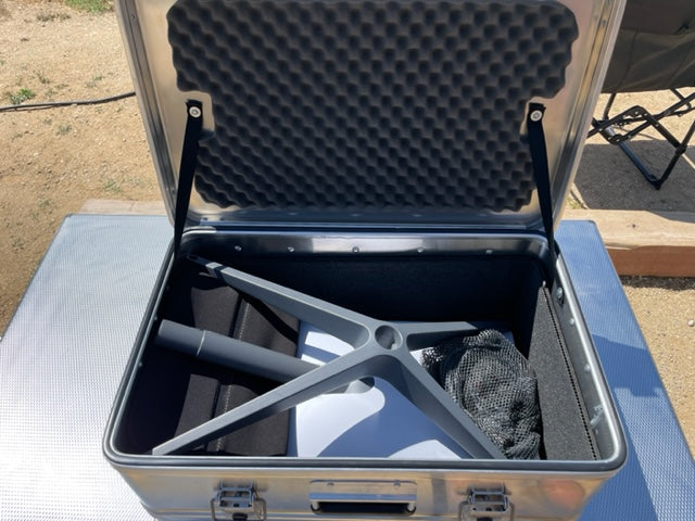 Aluminum camping storage case open outdoors with gear and foam padding inside