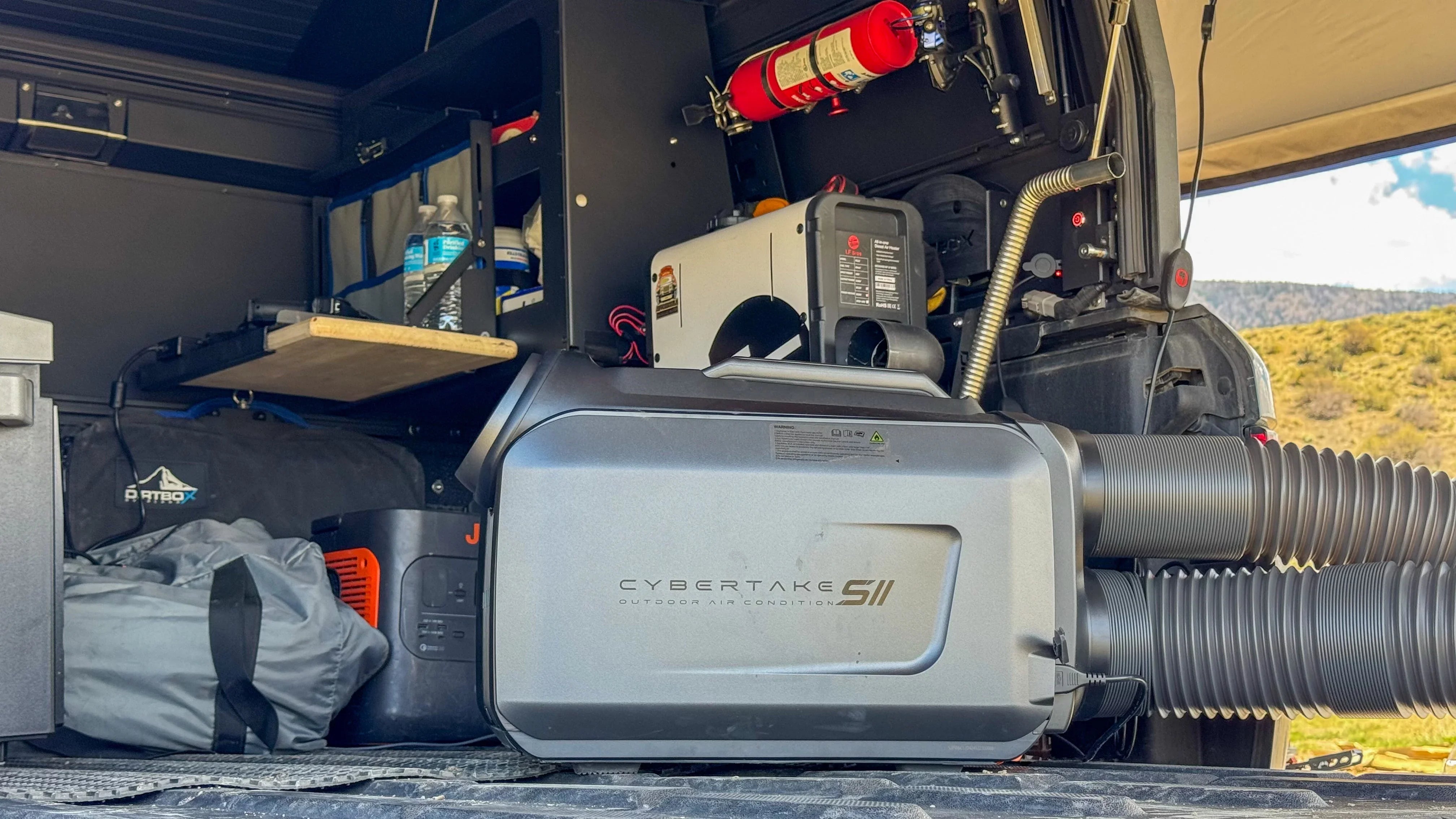 Portable outdoor air conditioner in an overlanding vehicle setup with camping gear and fire extinguisher