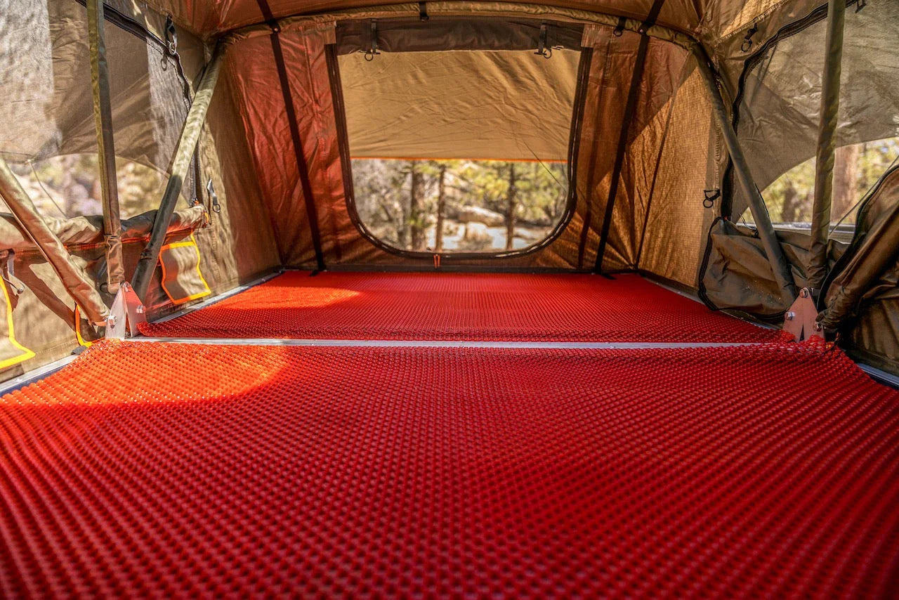 Overland rooftop tent interior with red gear mat for camping and adventure vehicles