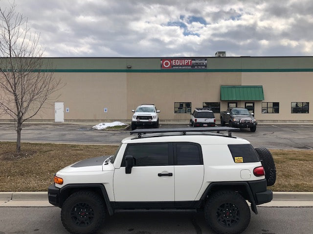 White Toyota FJ Cruiser with off-road tires parked outside commercial building
