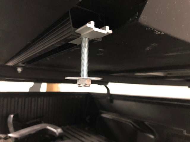 Close-up of a mounting bolt and bracket attached to a truck bed rail, overlanding accessory hardware