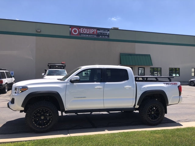 White Toyota Tacoma TRD Off-Road with roof rack parked outside expedition gear shop