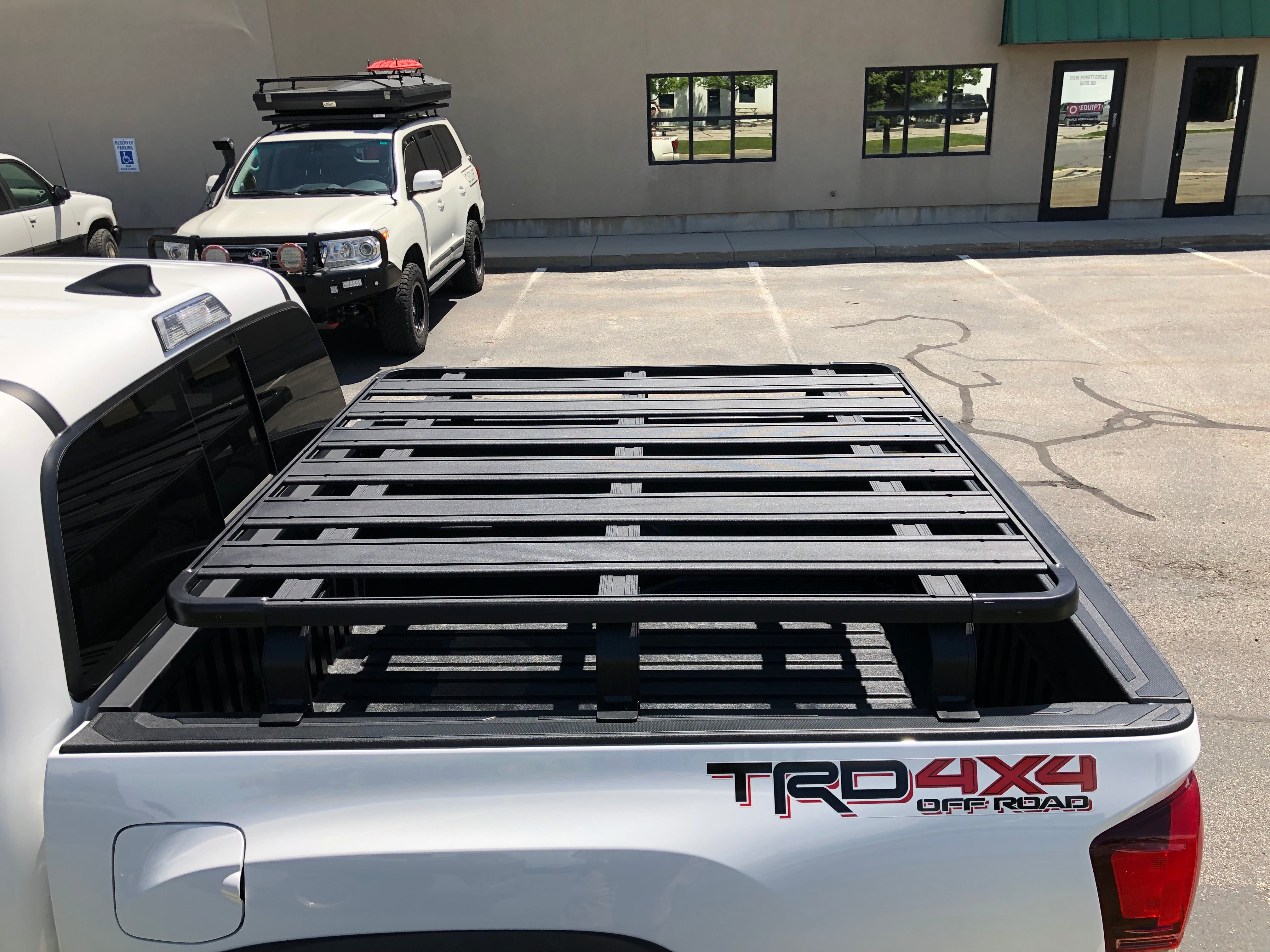 Toyota Tacoma with black overland bed rack in parking lot, TRD 4x4 Off Road decal visible