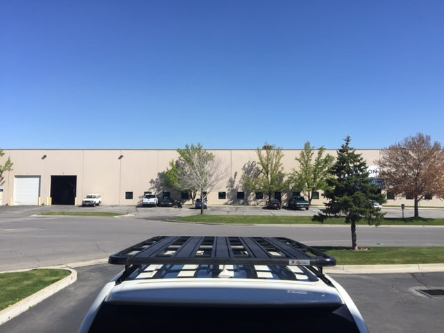 Roof rack mounted on a white SUV for overlanding and camping gear with warehouse in background