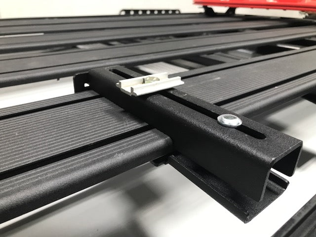 Close-up of black metal roof rack crossbar with mounting hardware for overland vehicles