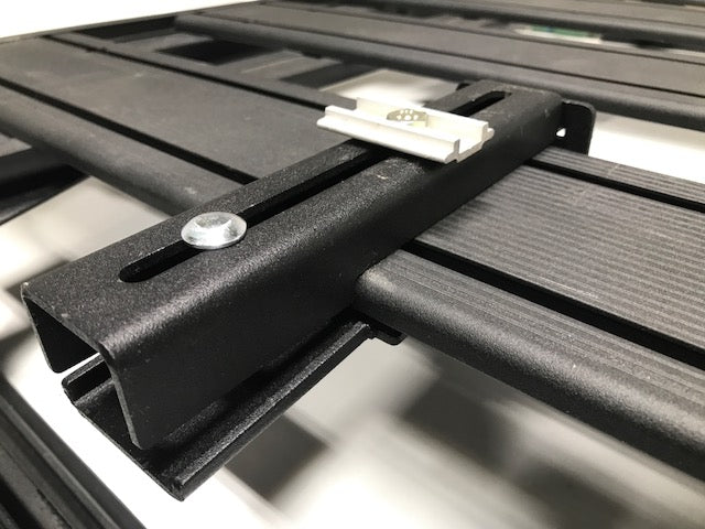 Close-up of black modular roof rack crossbar with mounting hardware for overlanding vehicles