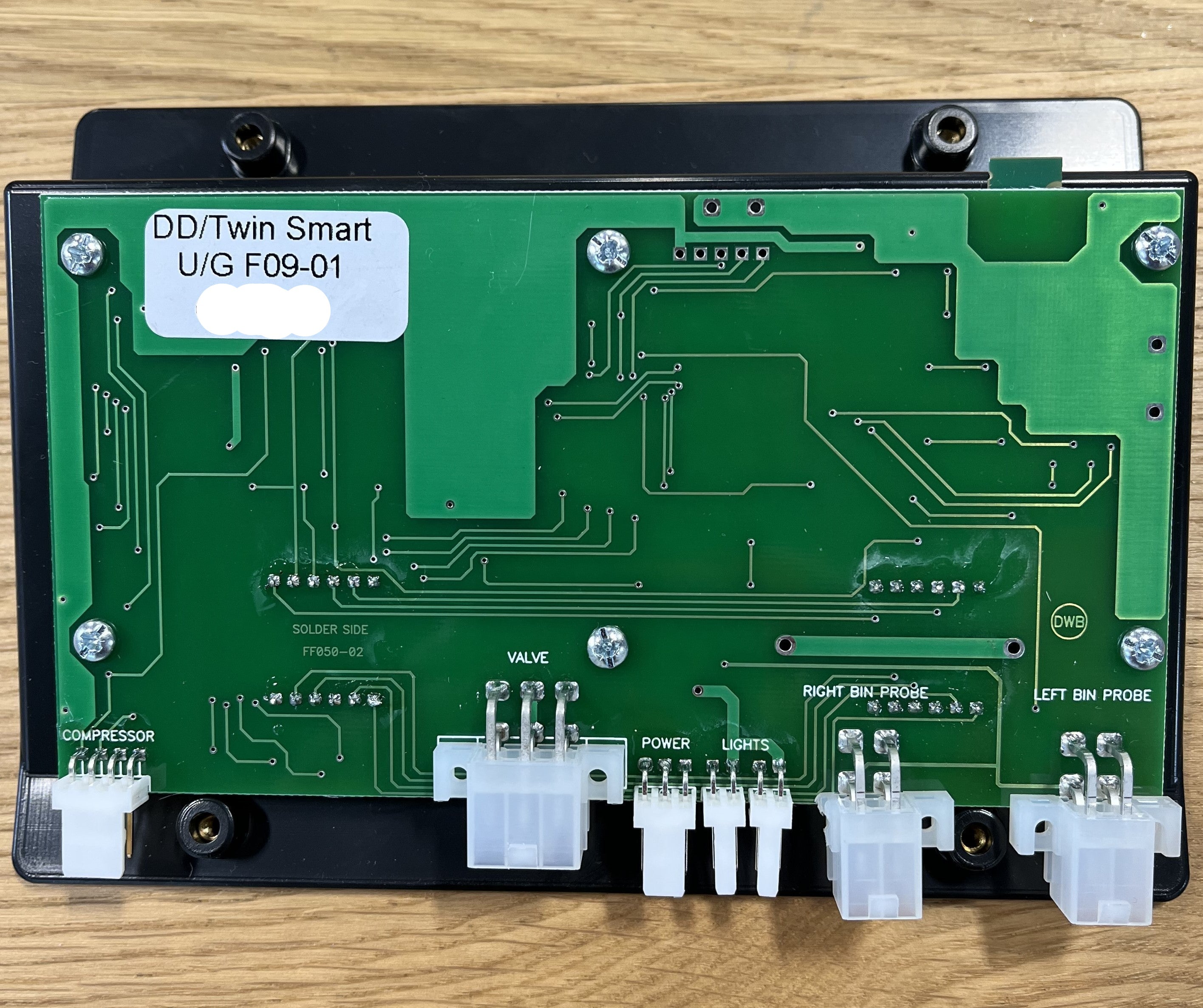 Electronic circuit board labeled DD/Twin Smart U/G F09-01 with connectors for compressor, valve, power, lights, and bin probes on a wooden surface