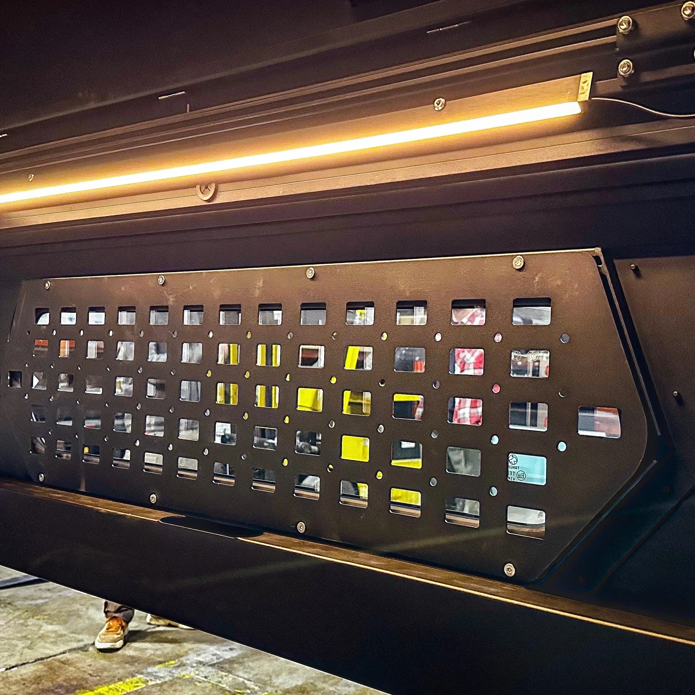 Close-up of a modular metal cargo panel and LED light bar for overlanding vehicles.