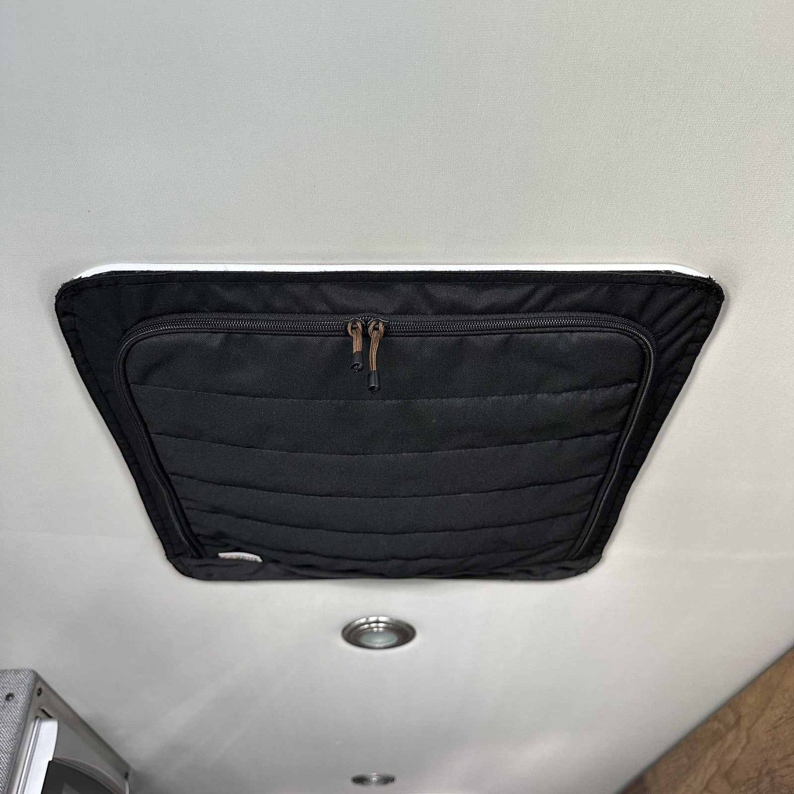 Black insulated ceiling vent cover with zipper for overland camper interior.