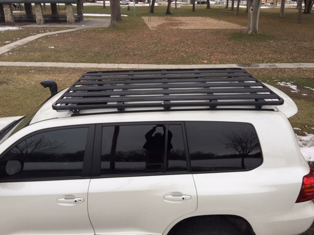 Black roof rack installed on white Toyota SUV for overlanding and camping gear transport