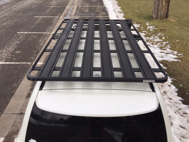 Black roof rack mounted on white SUV for overlanding or camping gear