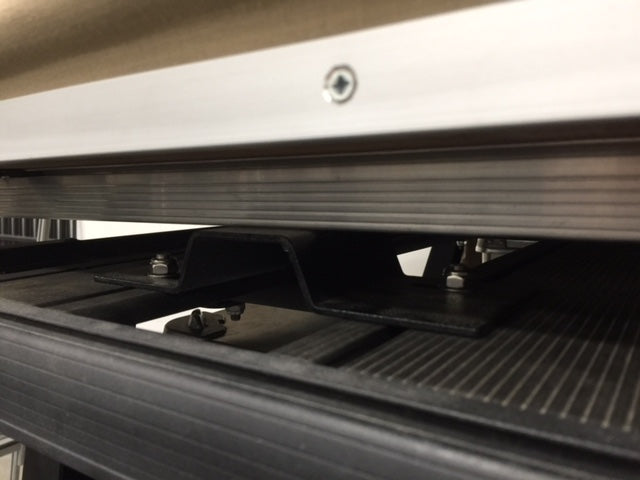 Close-up of metal mounting bracket and bolts on overland vehicle roof rack system