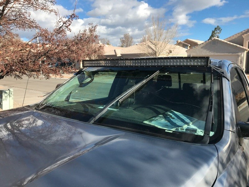 Truck with roof-mounted LED light bar for overlanding parked in suburban driveway