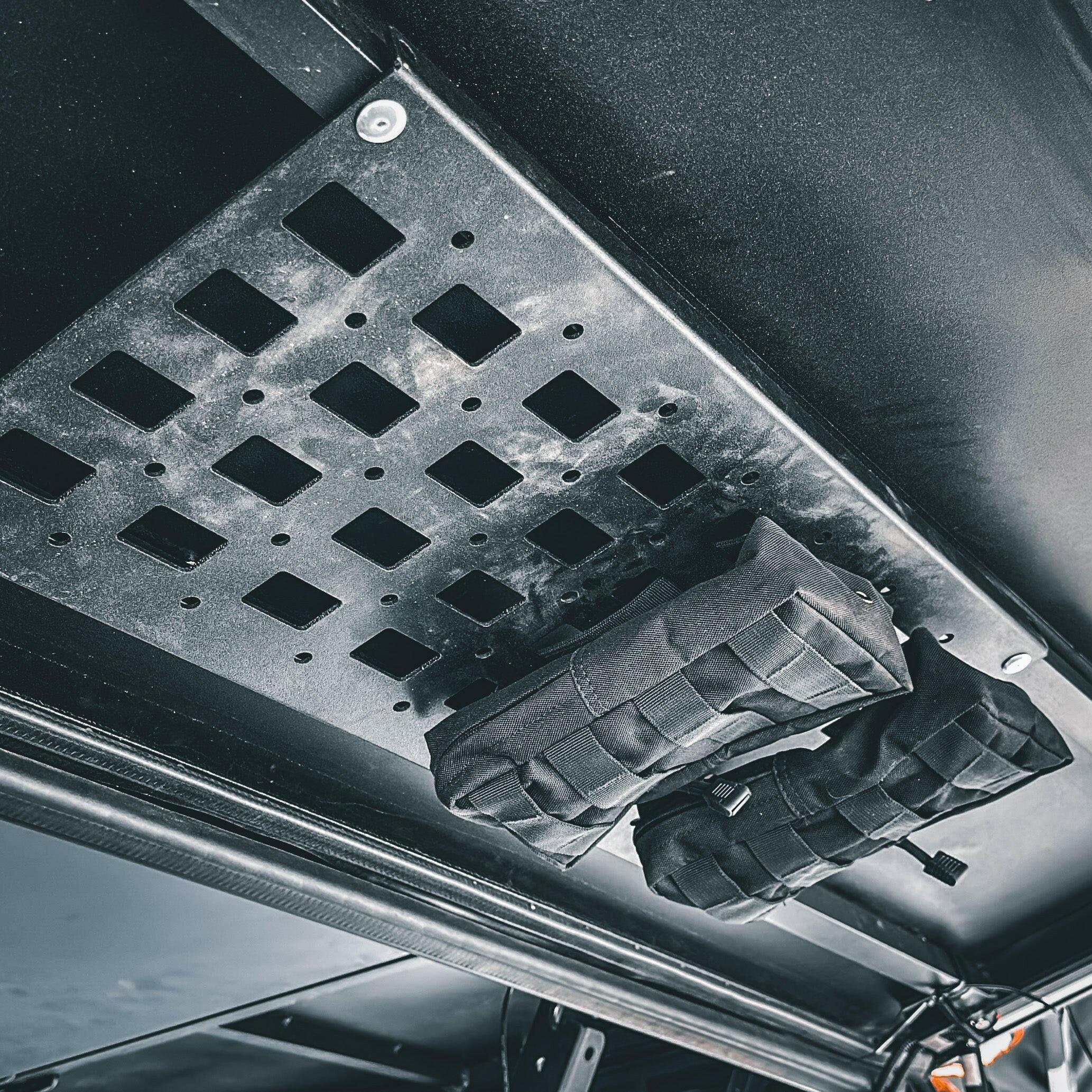 Overland vehicle molle storage panel with mounted black gear pouches, adventure camping setup
