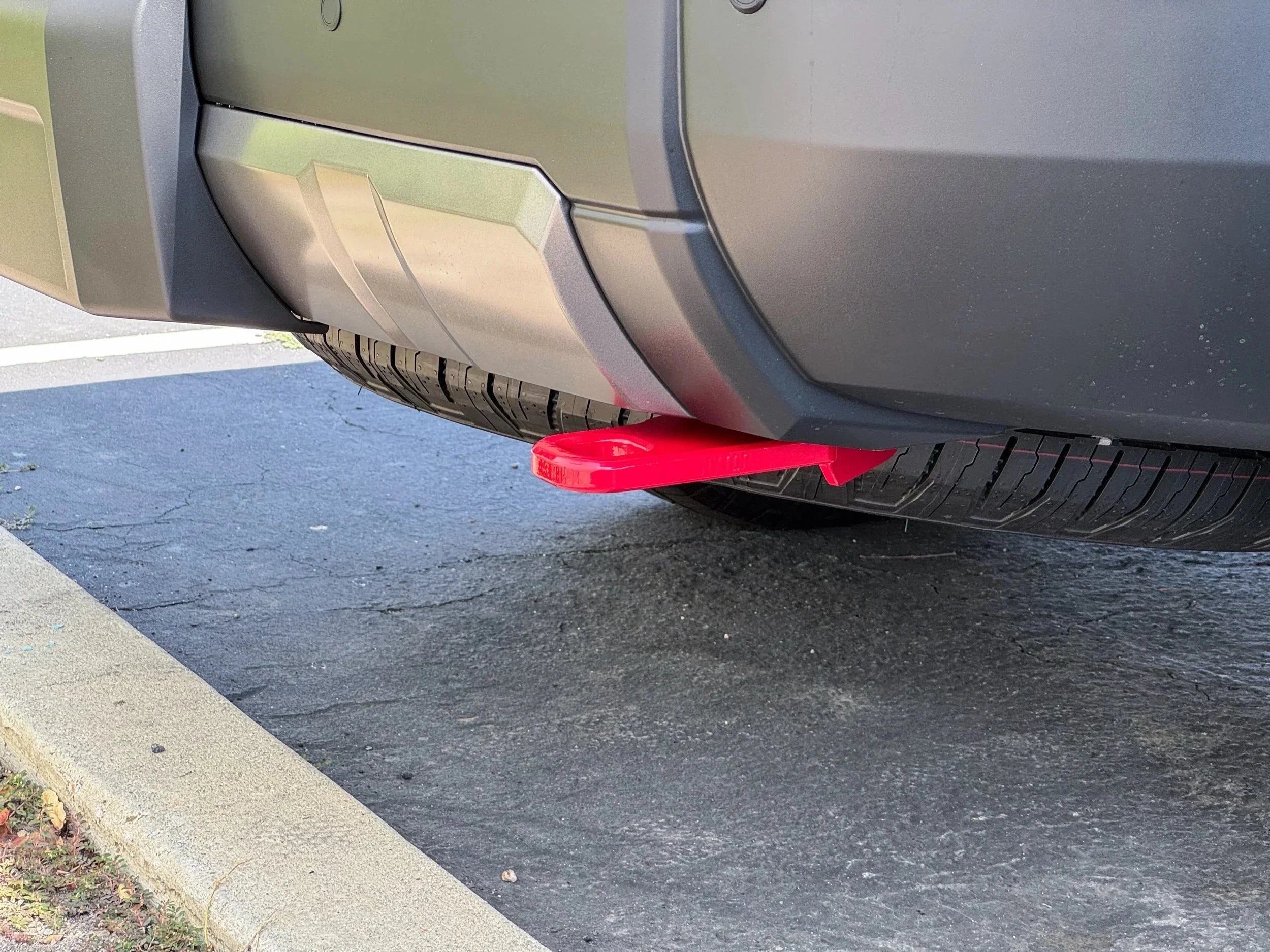 Red rear recovery point installed on off-road vehicle bumper, parked on asphalt