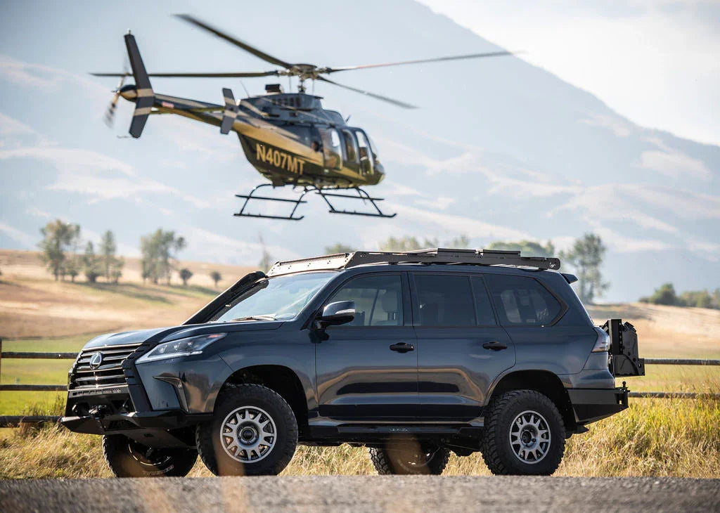 Lifted Lexus SUV with overlanding accessories parked in a field, helicopter flying above