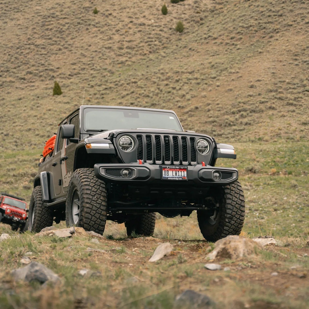 Jeep Gladiator with off-road rock sliders driving on rocky terrain outdoors