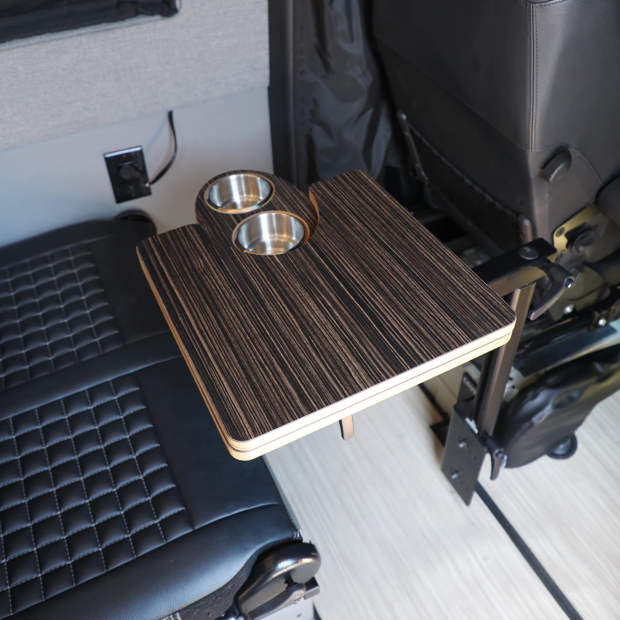 Vehicle interior with foldable wood camping table and two cup holders mounted between seats