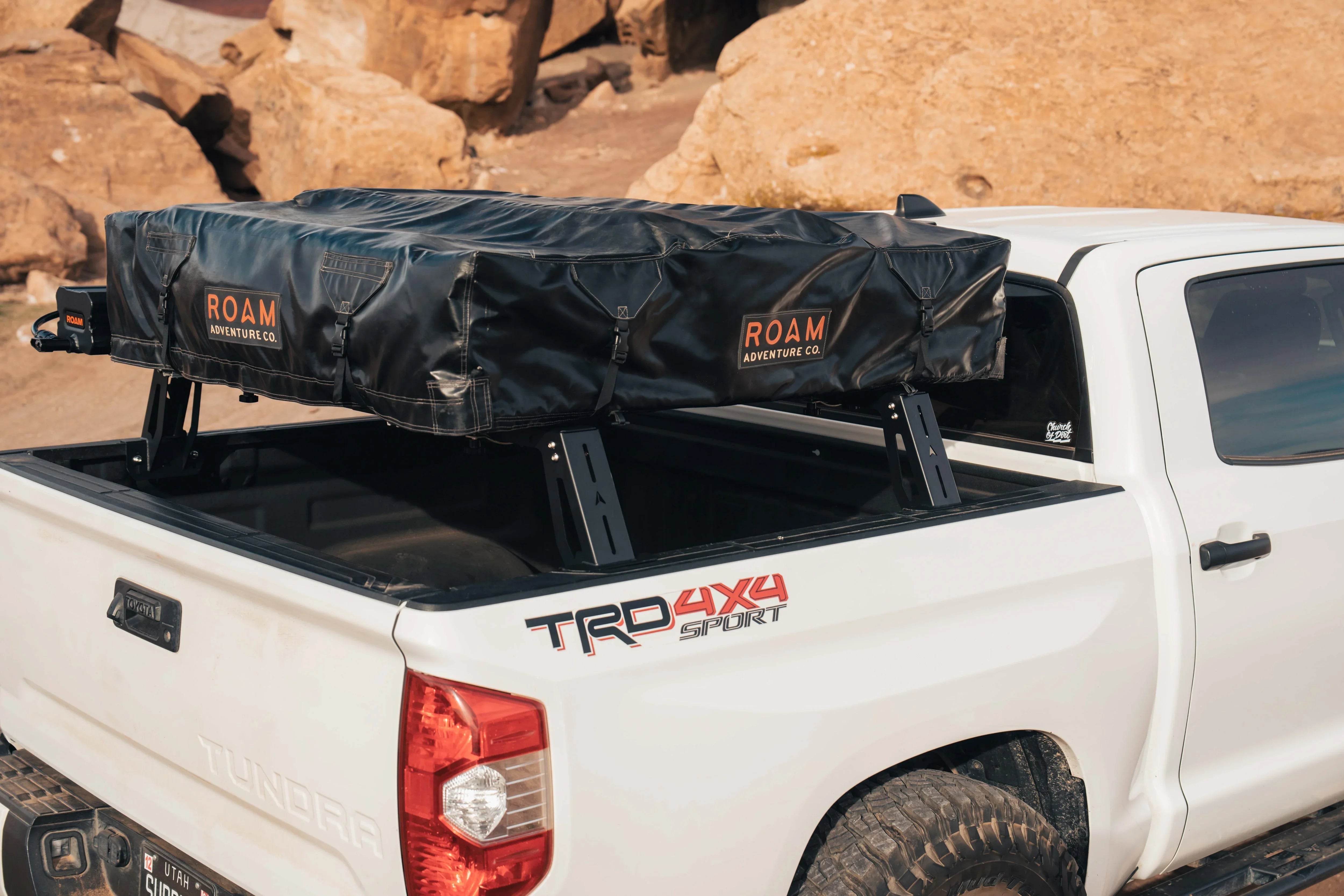 ROAM rooftop tent mounted on bed rack of white Toyota Tundra TRD 4x4 truck, off-road setting