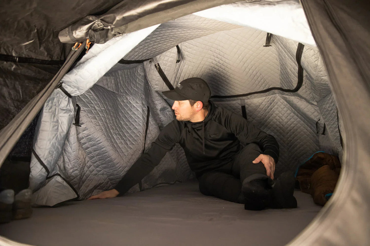 Man inside insulated rooftop tent for overlanding or expedition camping