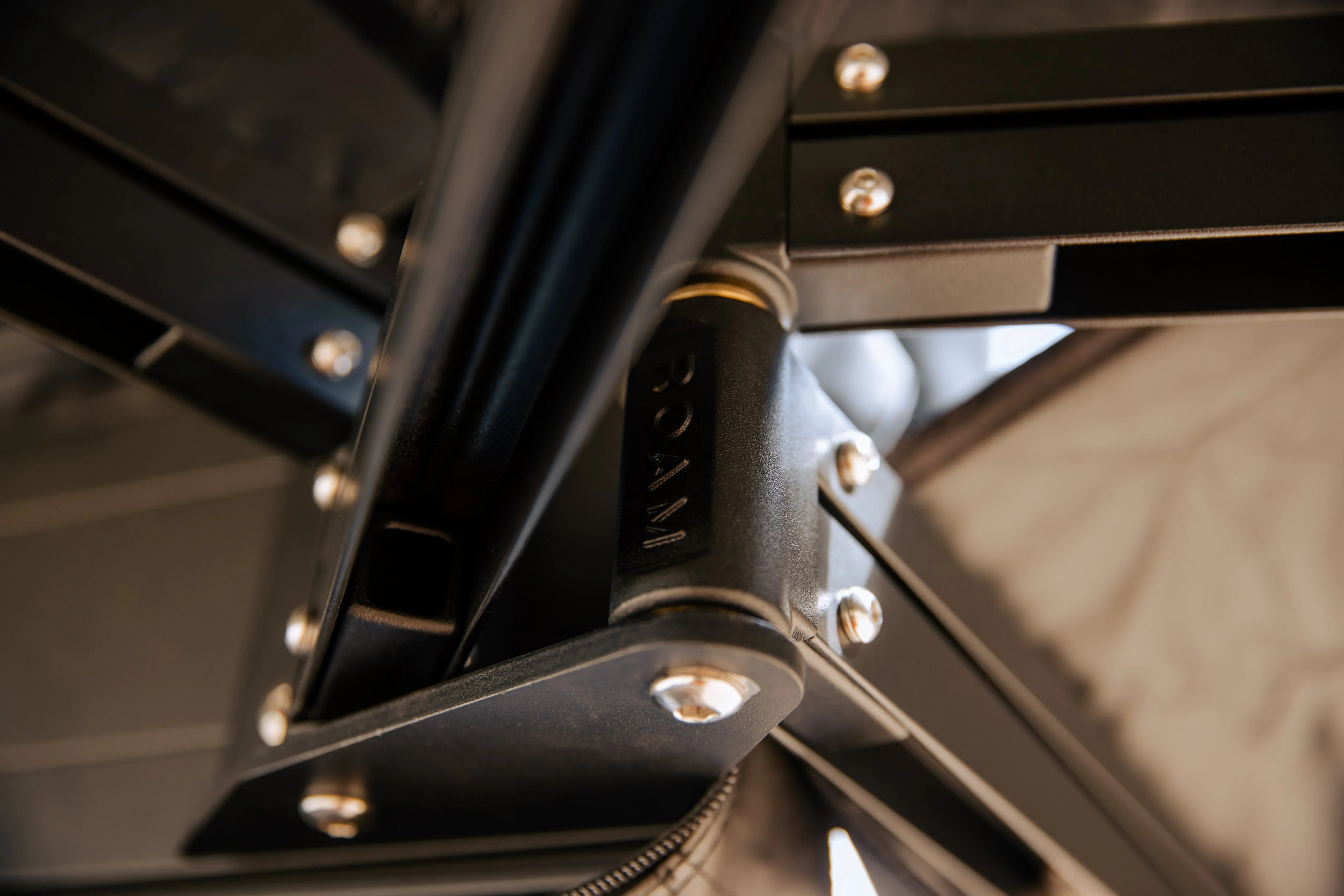 Closeup of ROAM branded black metal hinge and bolts on overlanding roof top tent support frame