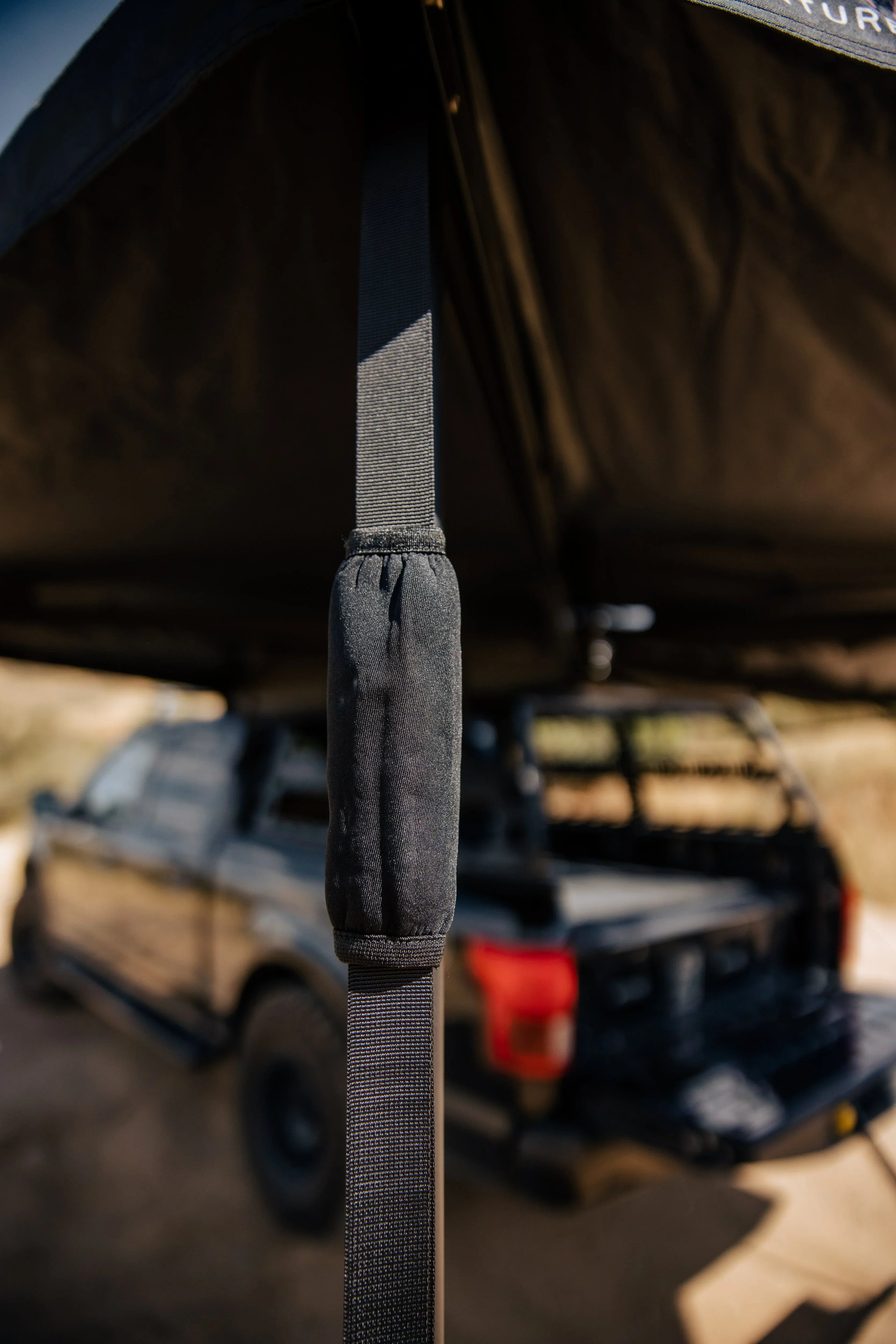Close-up of an awning strap attached to an overlanding vehicle in a desert setting