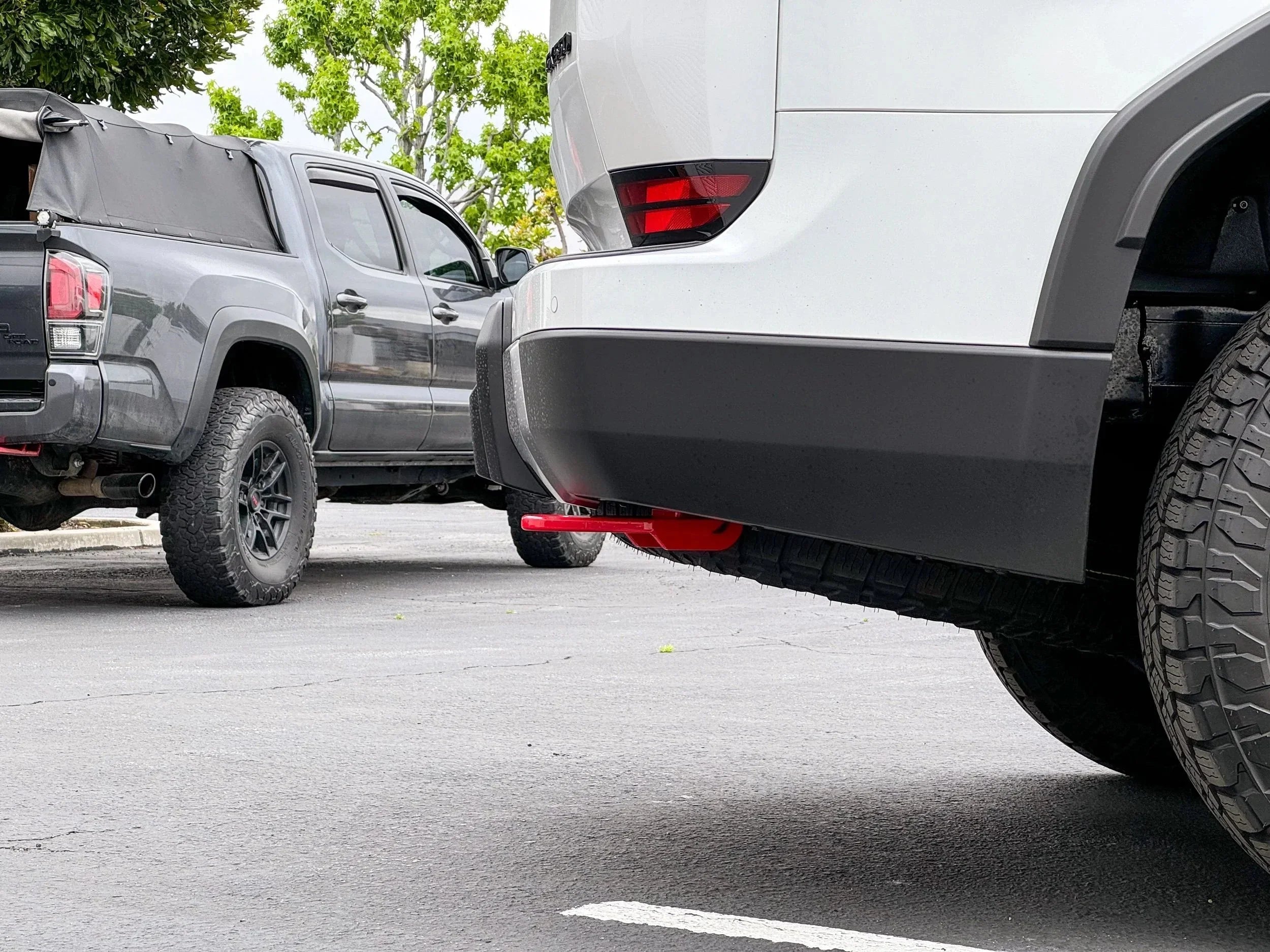 Toyota Tacoma and Toyota 4Runner with off-road tires and gear in a parking lot
