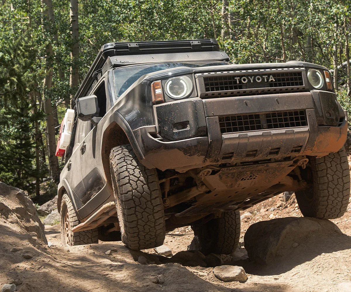 Toyota 4x4 SUV overlanding off-road on rocky forest trail with adventure gear