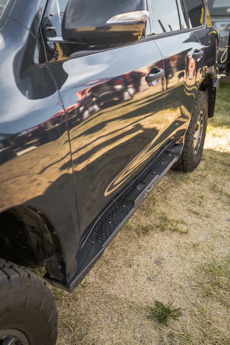 Lexus LX570 rock sliders installed on side of SUV, parked on grass, off-road ready