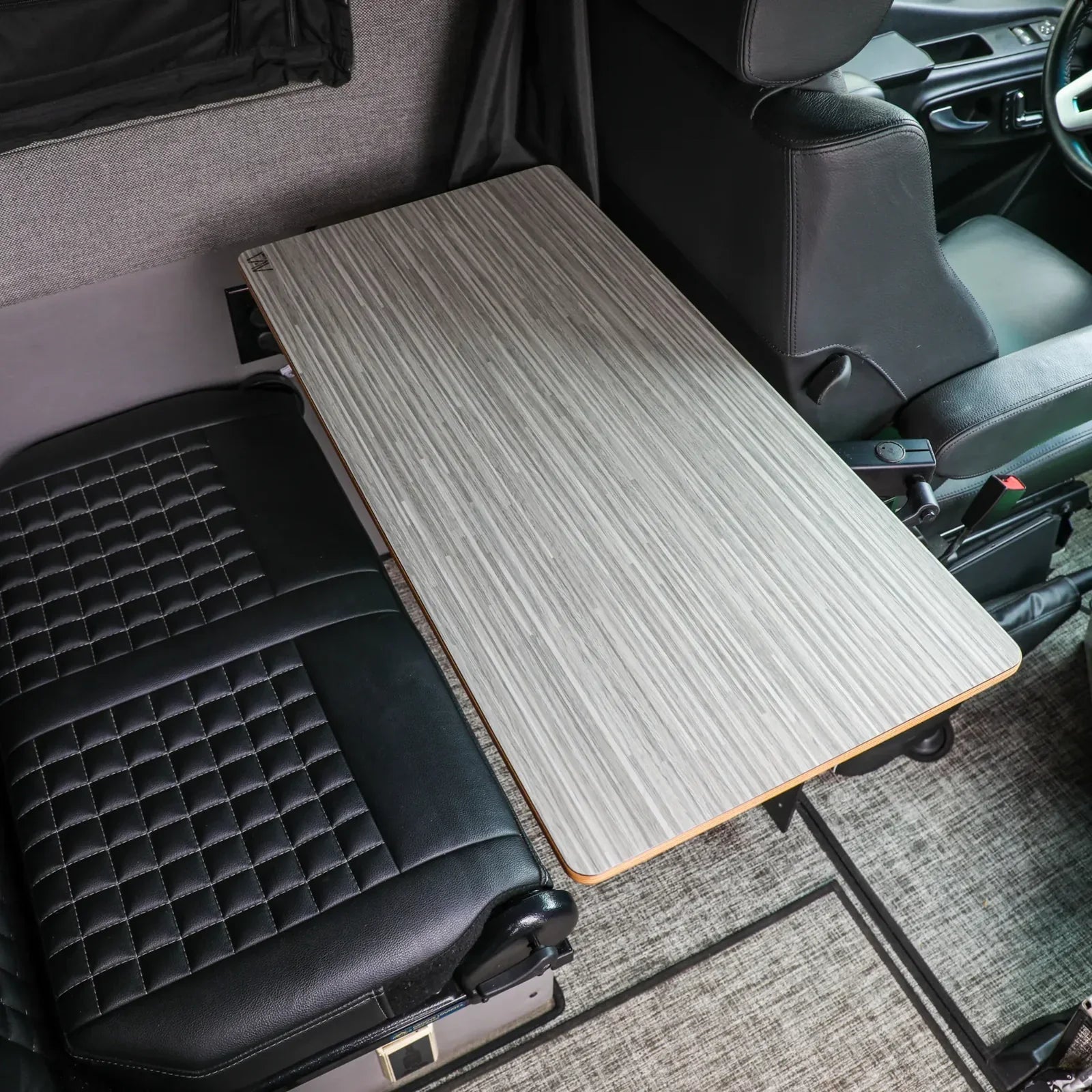 Vehicle interior with a mounted oak laminate camping table and quilted black seats