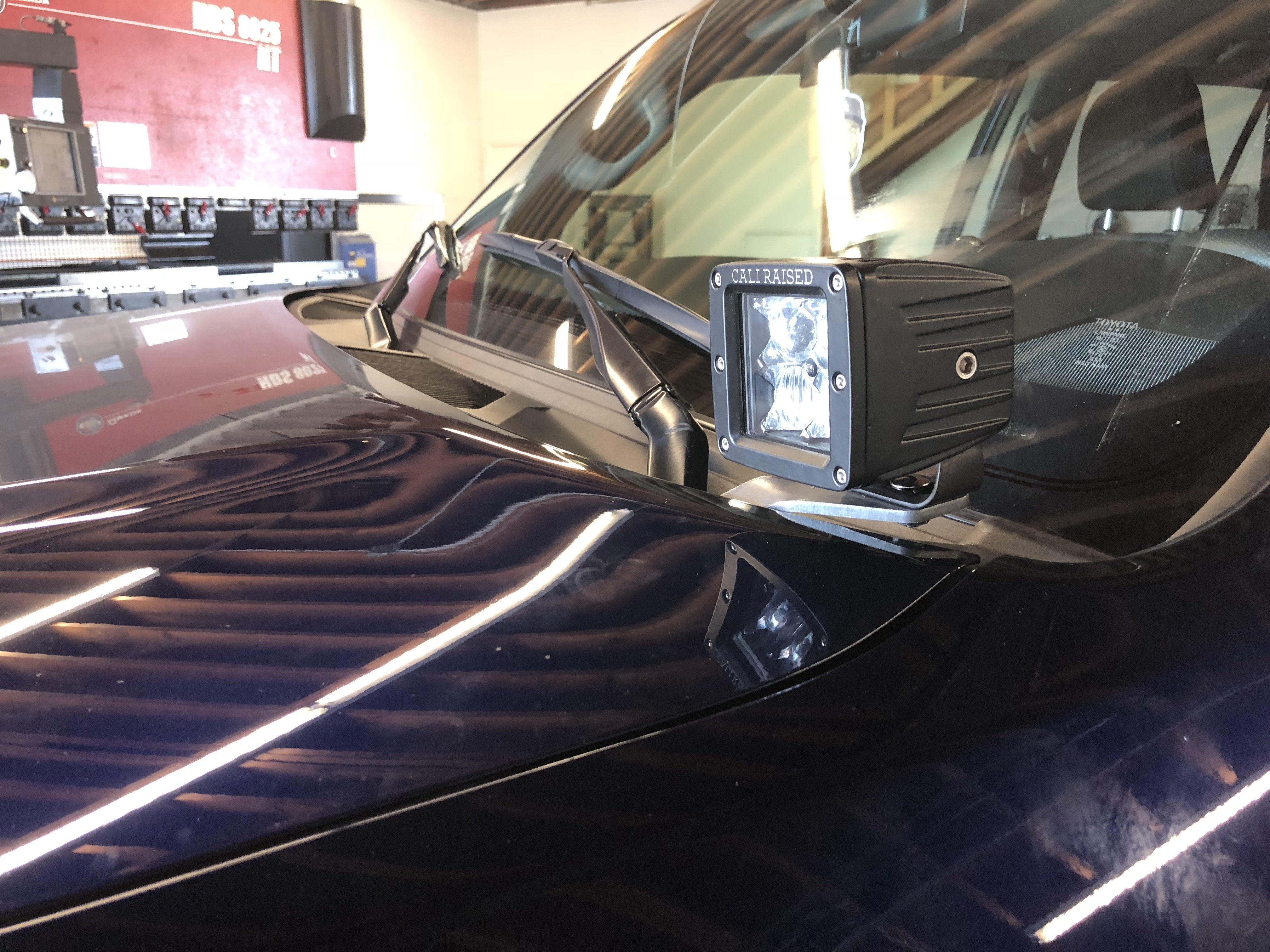 Square LED ditch light mounted on vehicle hood bracket for off-road overlanding