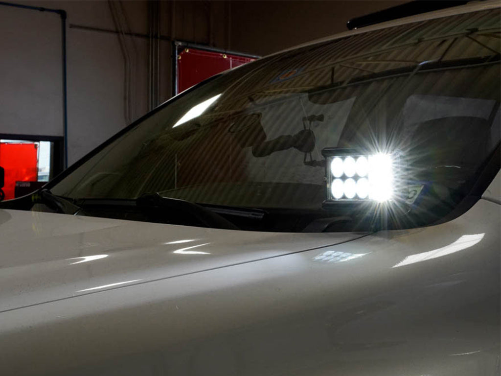 Off-road LED ditch light mounted on vehicle hood near windshield, illuminated indoors