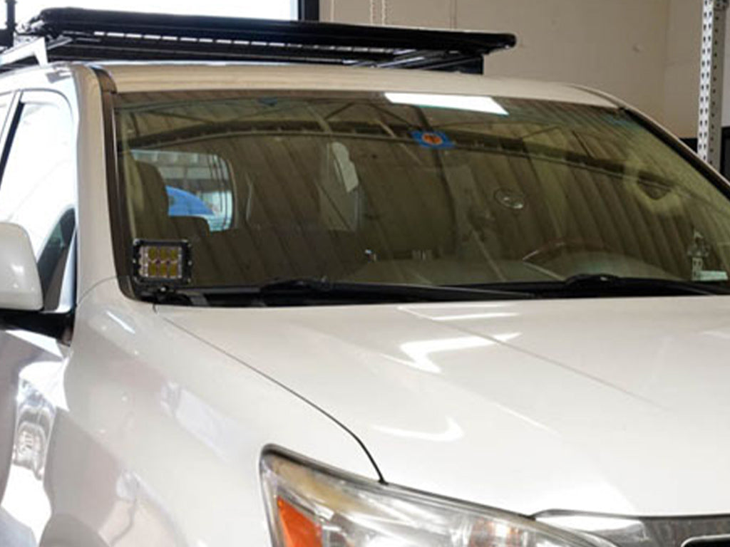 White SUV with roof rack and aftermarket ditch light bracket installed on windshield pillar