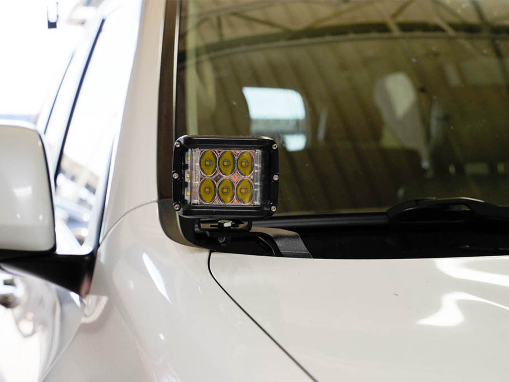 Off-road LED ditch light mounted on white SUV windshield bracket