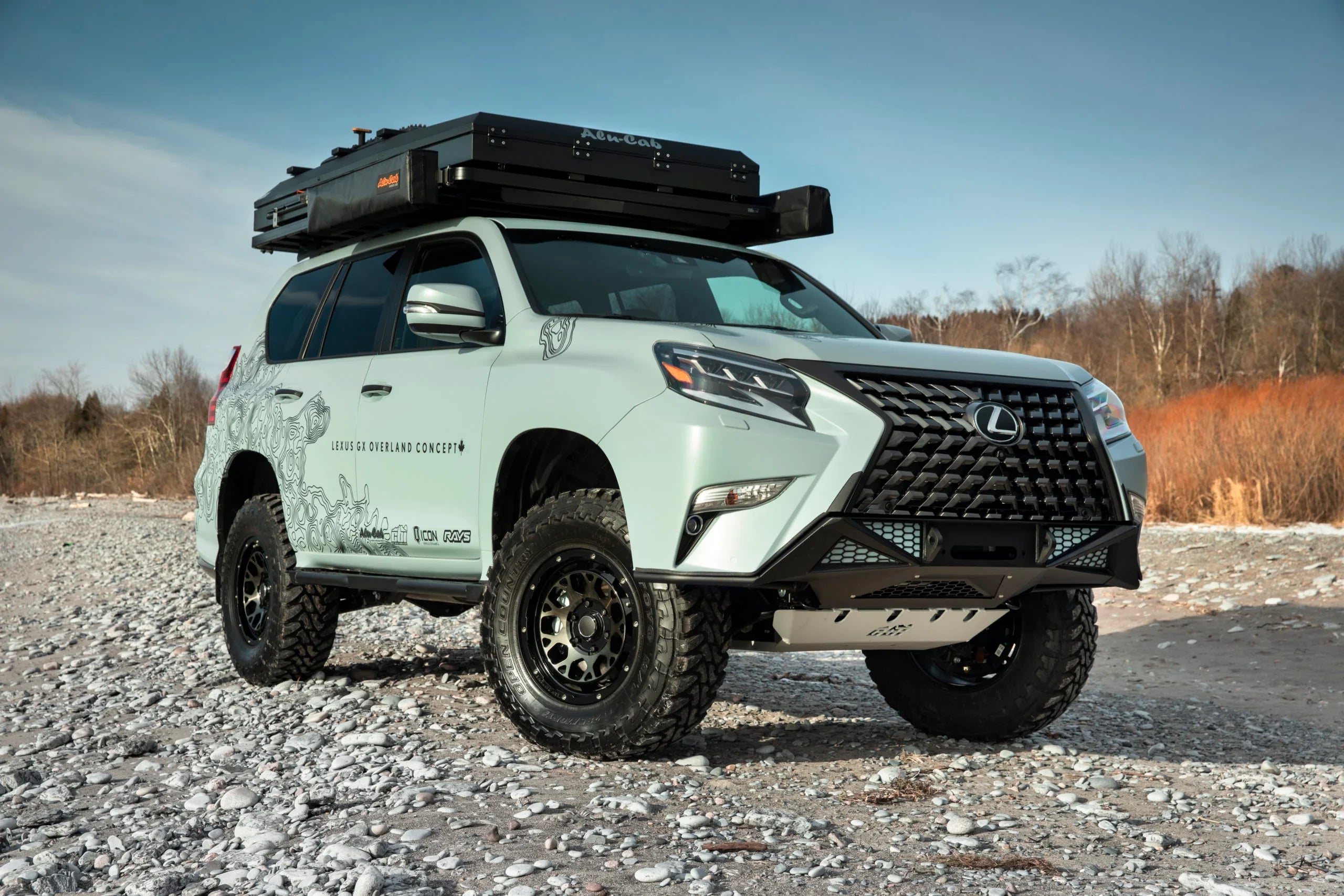 Lexus GX overland SUV with roof rack and off-road tires on rocky outdoor terrain
