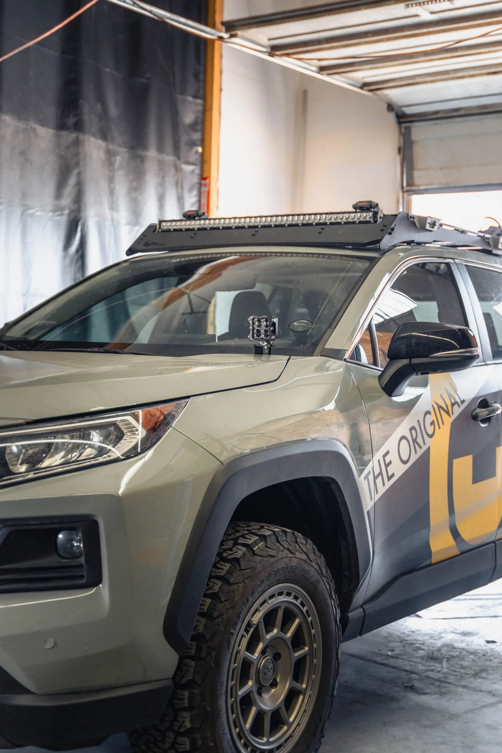 Toyota RAV4 with aftermarket ditch light brackets and off-road lighting in garage
