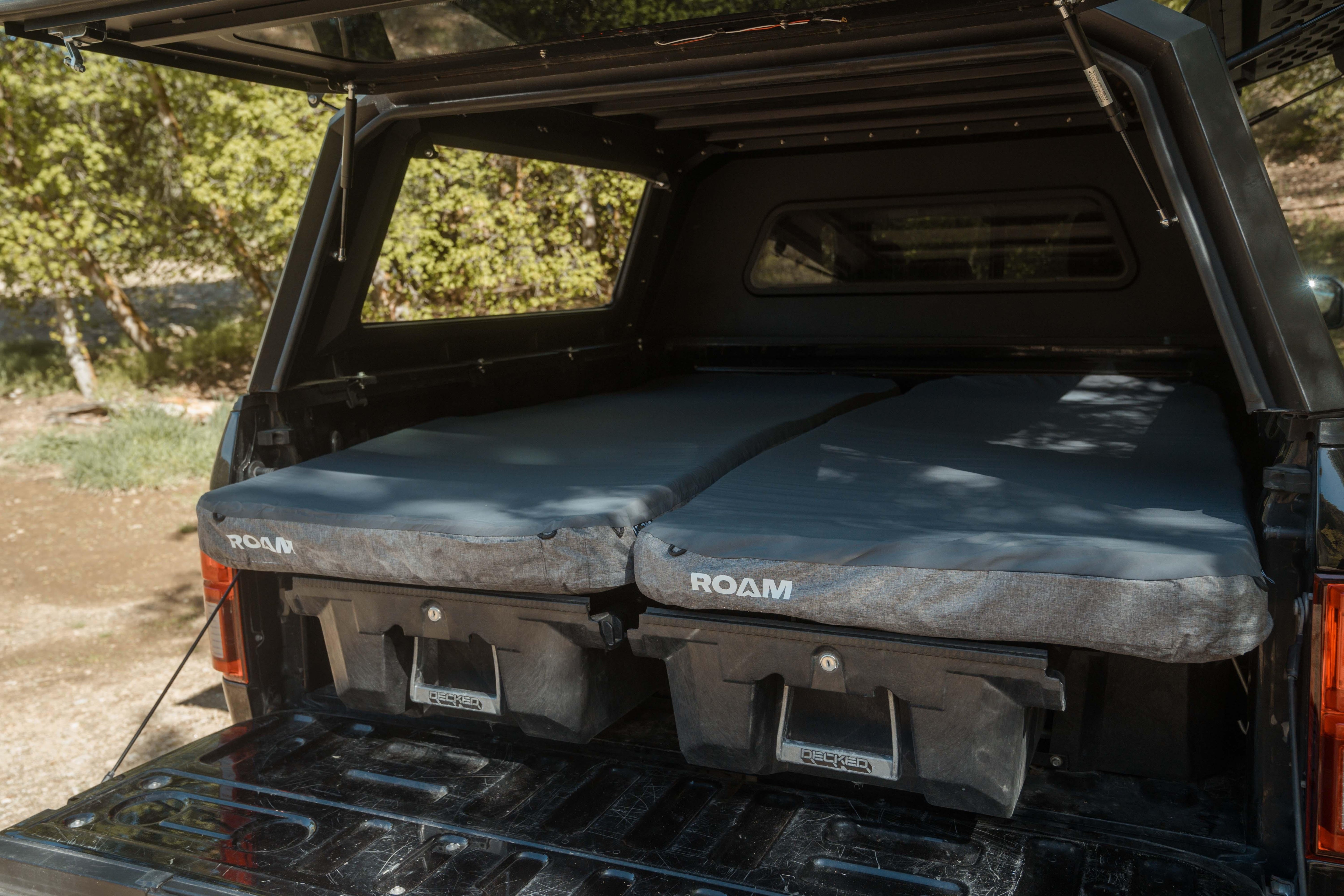 Overland truck bed with dual ROAM sleeping pads and storage drawers, ideal for camping gear.