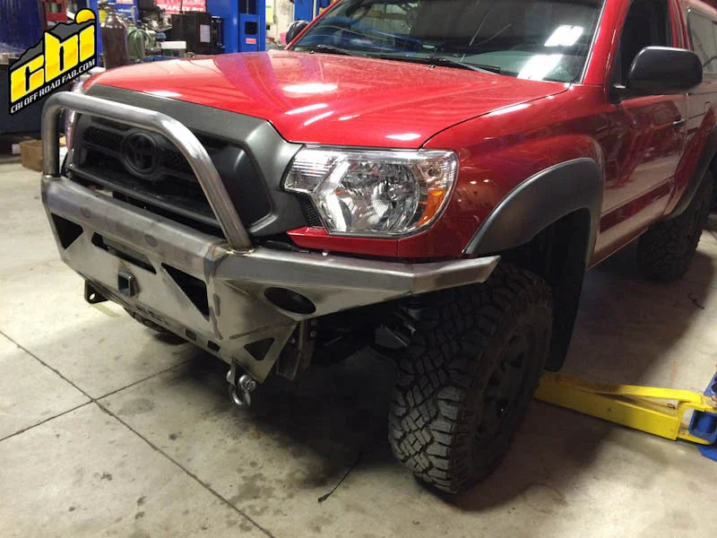 Red Toyota Tacoma with steel off-road front bumper and grille guard in a garage