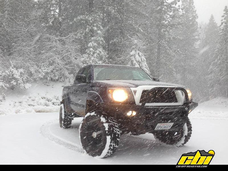 Toyota Tacoma with off-road bumper and snow tires in snowy forest setting