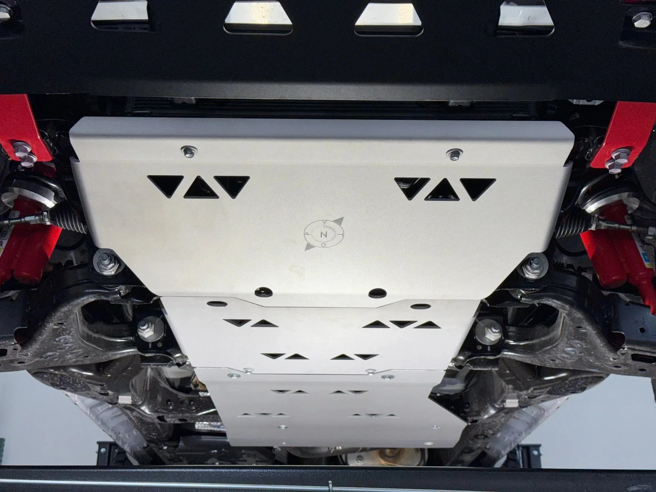 Heavy-duty skid plate installed under off-road vehicle, showing protection for suspension and undercarriage.
