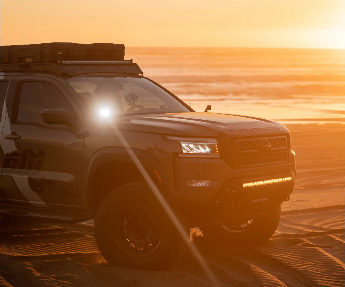 Nissan Frontier overland truck with roof rack and off-road gear on Oregon Coast at sunset