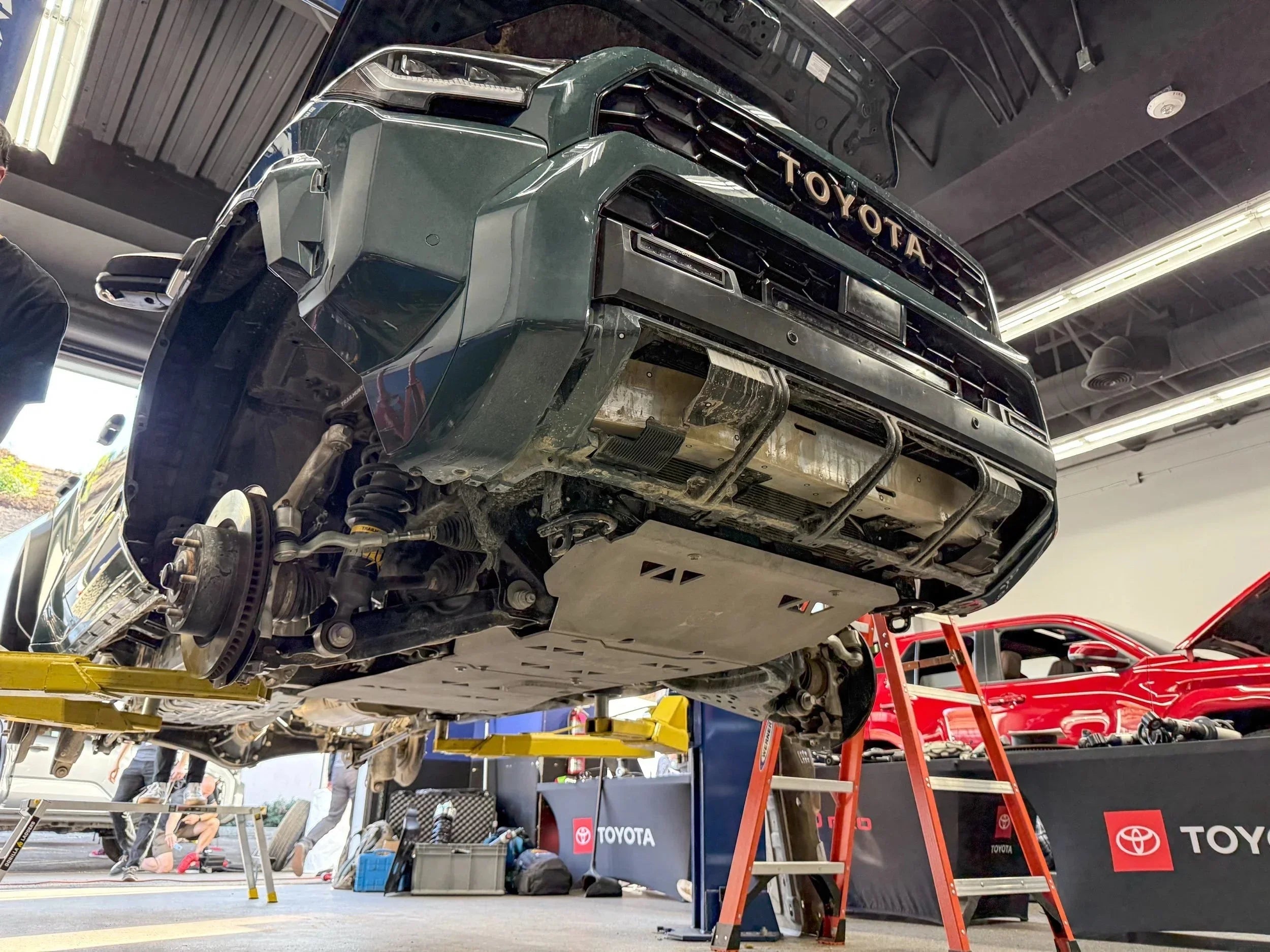 Lifted Toyota truck in a garage with visible skid plate and suspension, overlanding setup