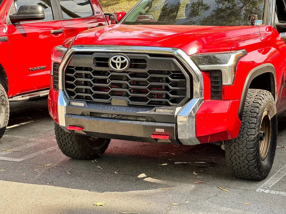 Red Toyota Tundra trucks with off-road tires and rugged front grilles parked outdoors